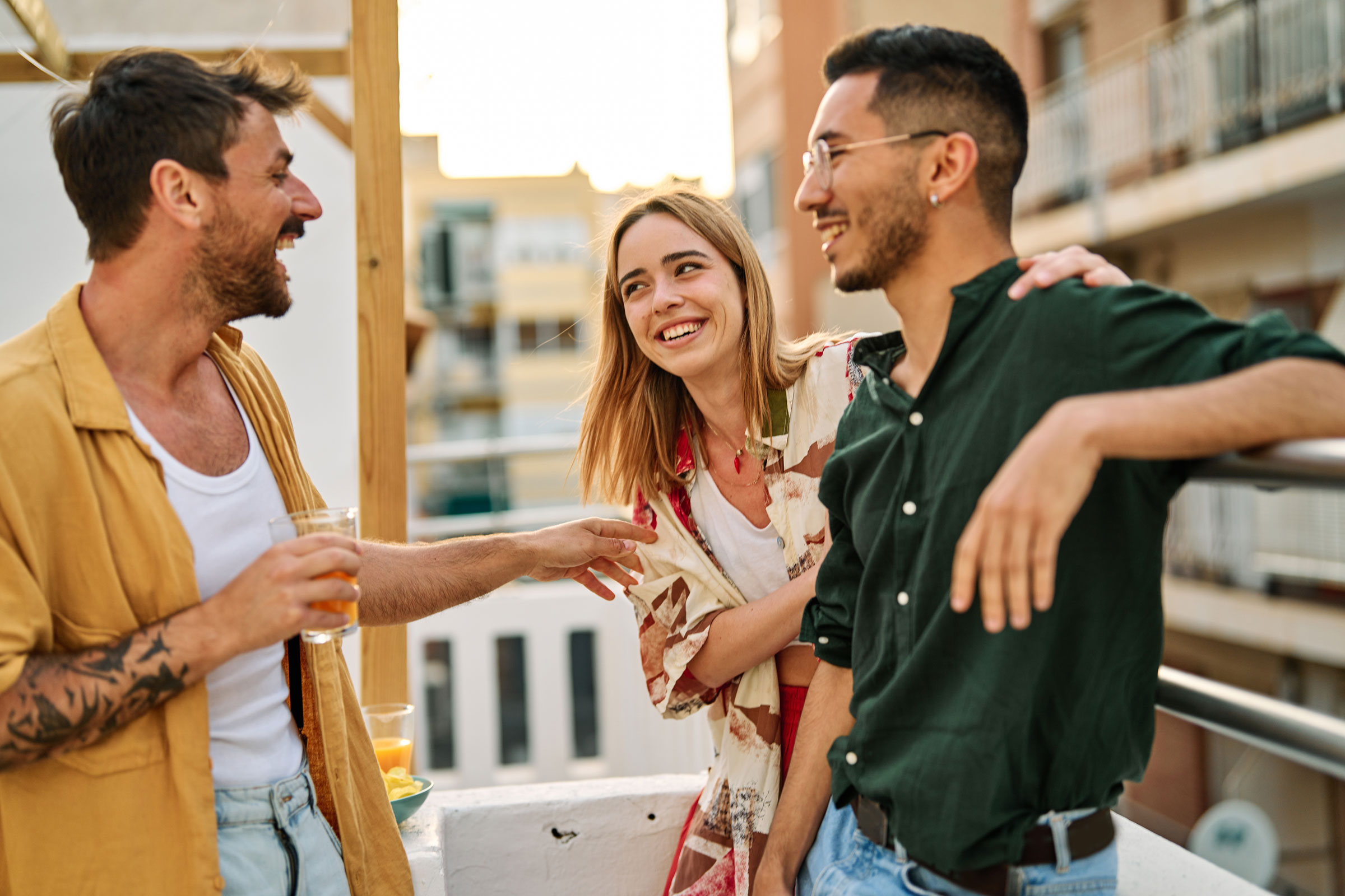 Drei lächelnde Freunde nutzen die BBVA App auf einem Smartphone, um am Freunde werben Programm teilzunehmen und sich Prämien zu sichern.
