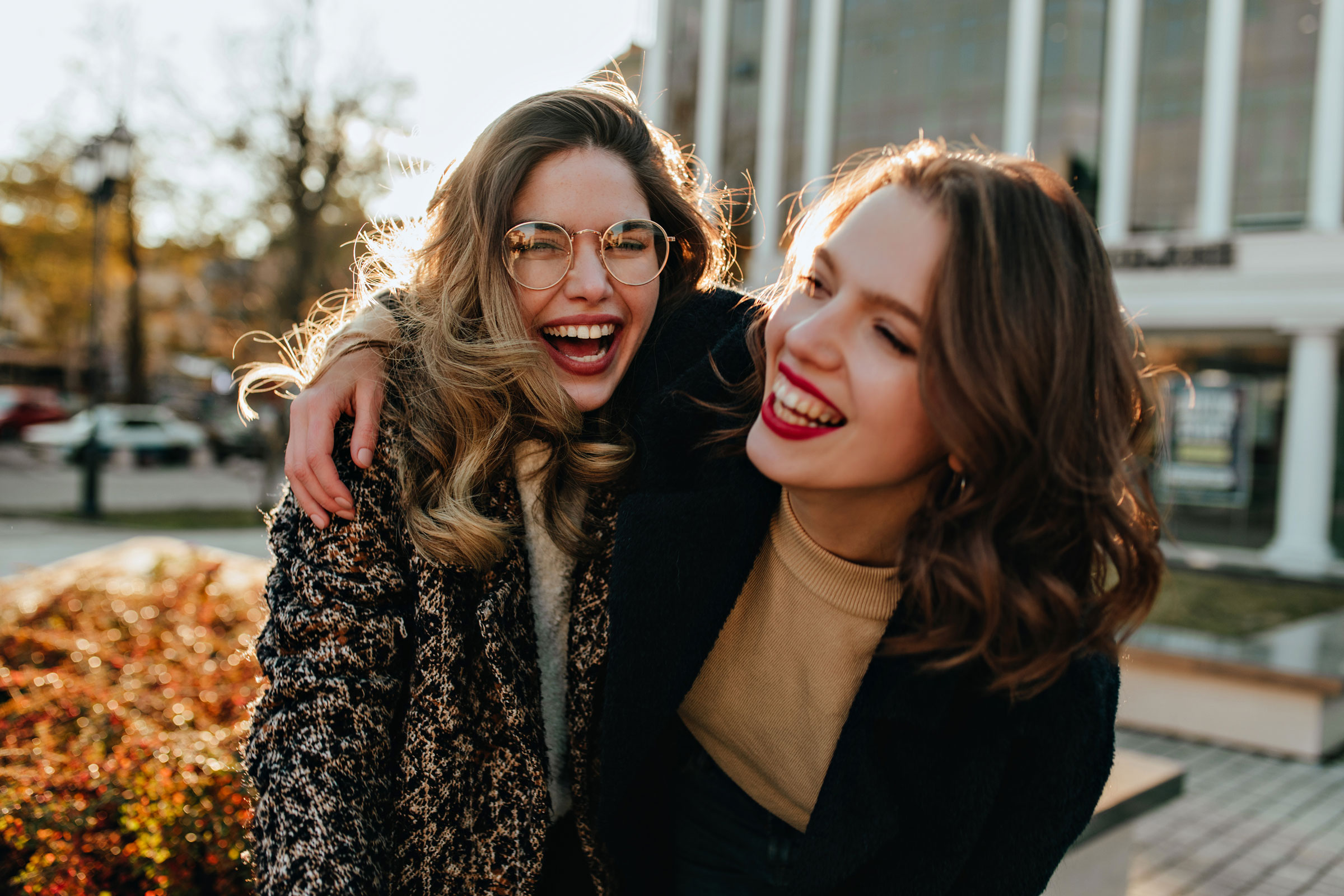 Two smiling friends using the BBVA App on a smartphone to participate in the Refer a Friend program and secure rewards.