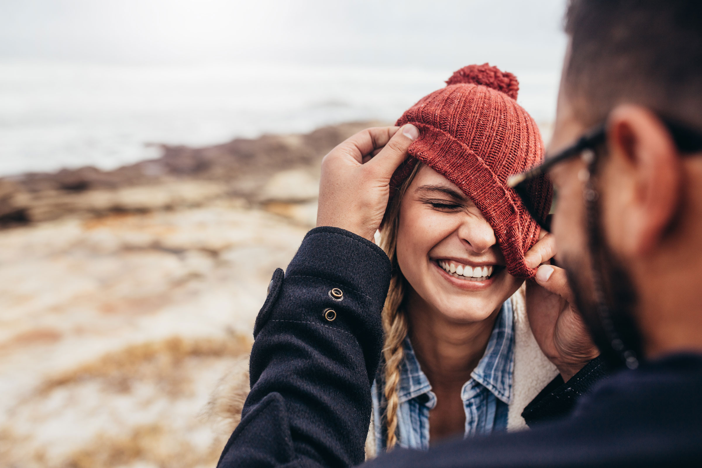 A person adjusting another person's hat outdoors