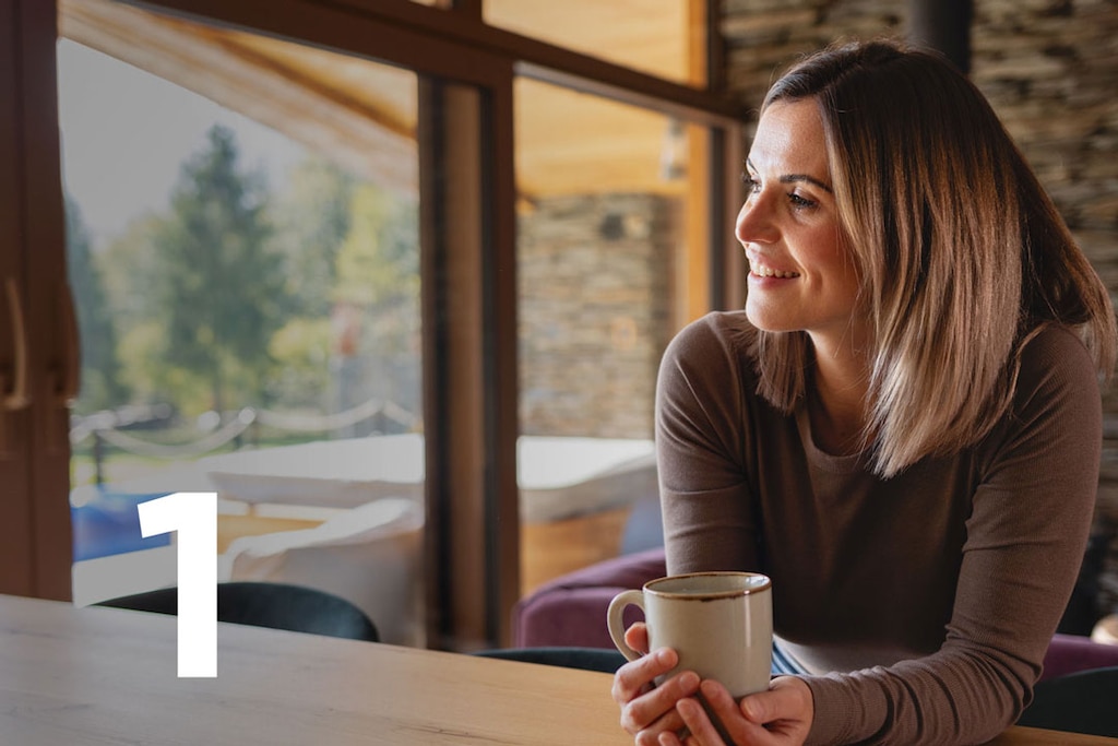Woman with a coffee cup is selecting travel insurance in the BBVA App's "Products" section.