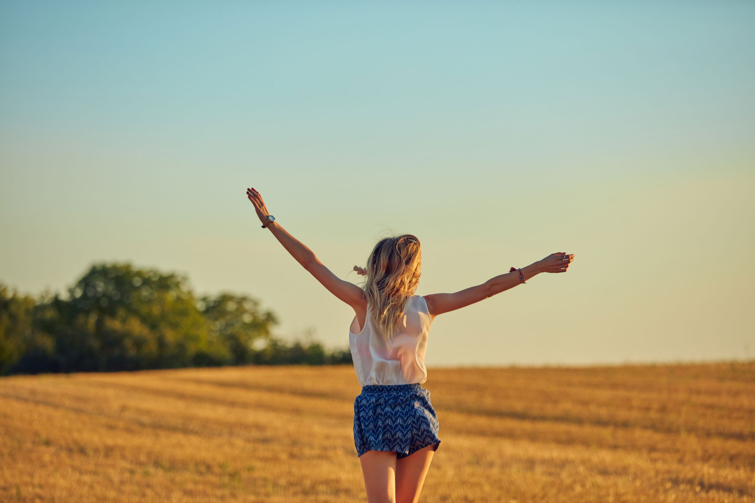 Person steht auf einer Wiese mit ausgestreckten Armen – Symbol für globale Reichweite von BBVA